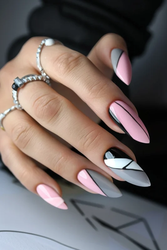 Stiletto nails with pink and grey color blocks separated by black lines.