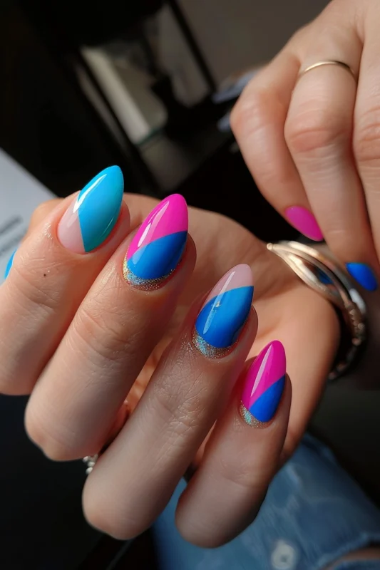 Nails with a color block of hot pink, blue, and a touch of gold glitter.