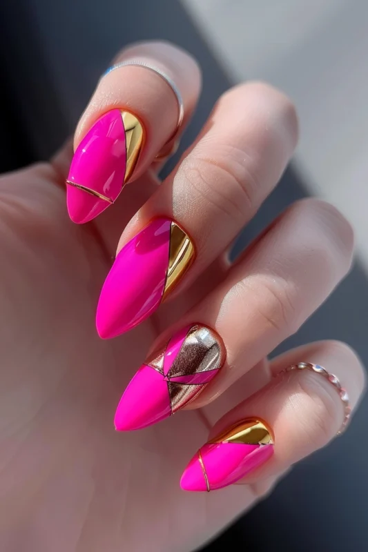 Hot pink stiletto nails with gold foil accents and chevron patterns.