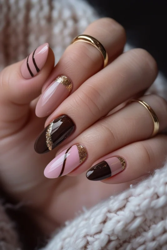 Almond-shaped nails with pink, brown, and gold glitter.