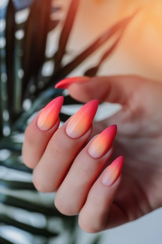 Almond-shaped nails with a pink and orange sunset ombre effect.