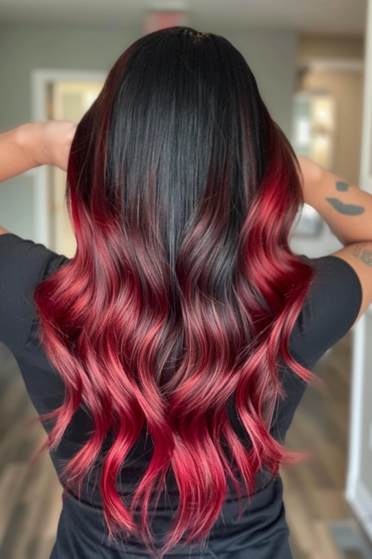 Back view of long black hair with a bold crimson red ombre, styled in loose waves.