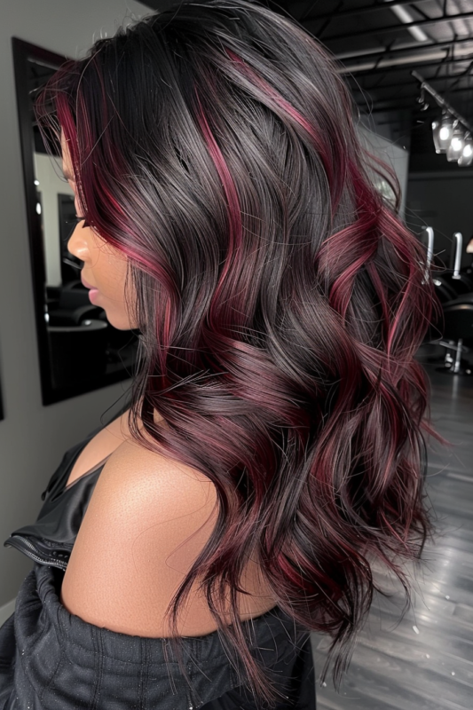 Side view of black hair with subtle burgundy highlights, styled in soft waves.