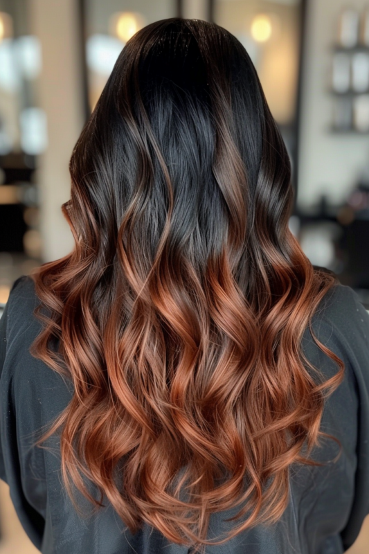 Back view of long black hair transitioning to a warm copper ombre, styled in loose waves.