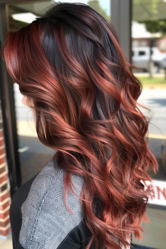 Wavy black hair with subtle copper balayage highlights.
