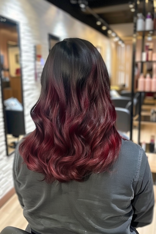 Black hair with dark cherry red highlights blended subtly.