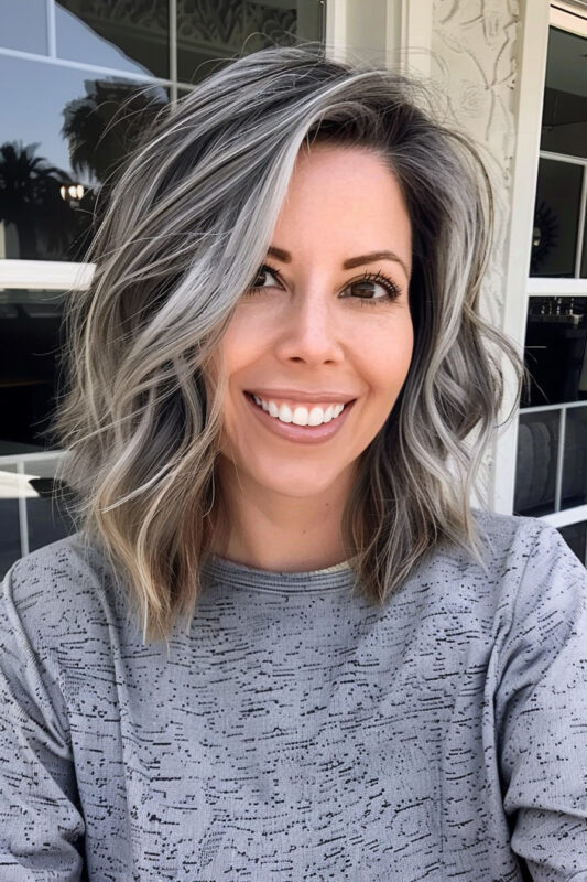 Woman with smooth, layered salt and pepper hair, blending dark and light gray tones with a side part.