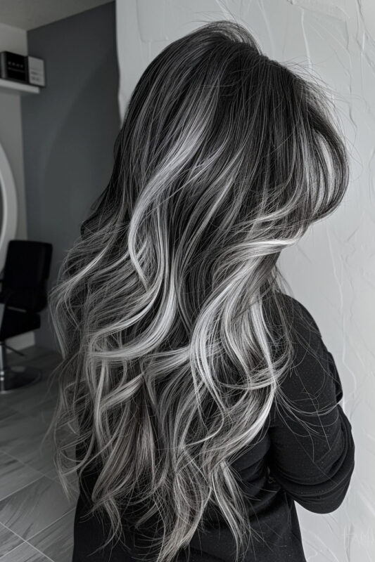 Wavy black hair with natural and dyed silver highlights.