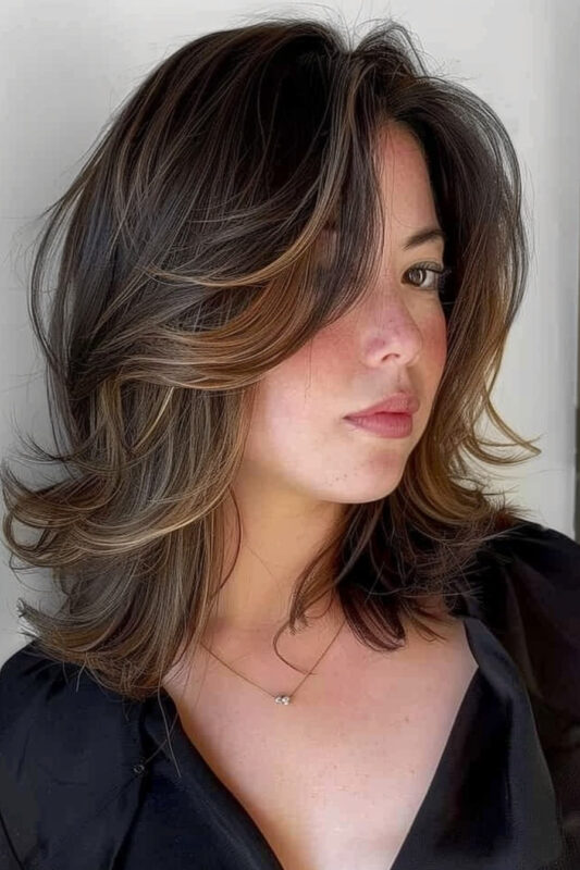 Woman with a butterfly cut with curtain bangs on brown hair.