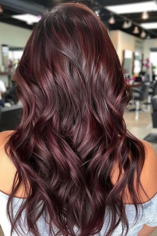 A woman with chocolate cherry hair color, a dark brown base with vibrant cherry red undertones.