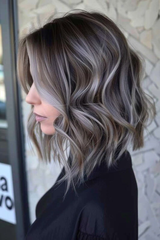 Woman with a wavy bob and brown hair with silver highlights, blending seamlessly.