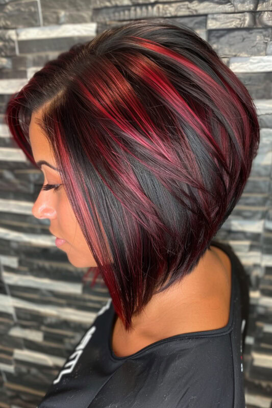 A woman with a short angled bob haircut on black hair with red highlights.