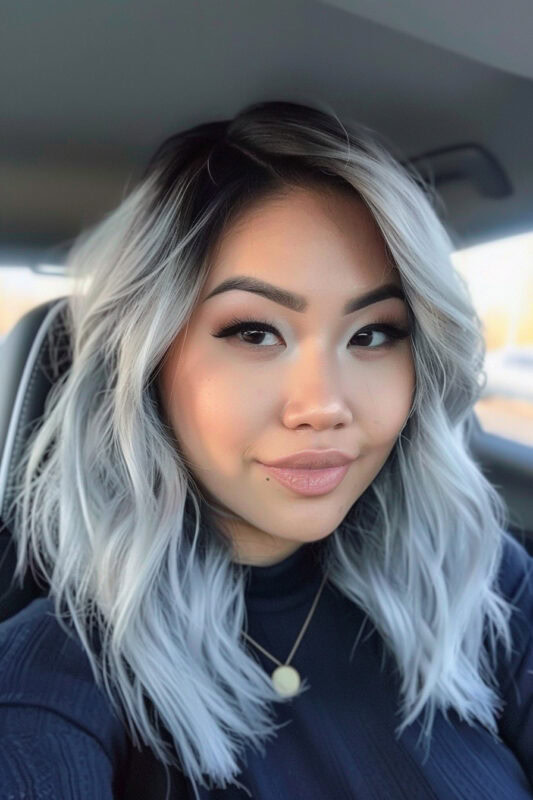 Woman with long silver hair and dark shadow roots.