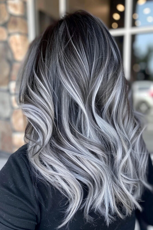 Woman with loose wavy hair featuring a silver ombre effect and highlights.