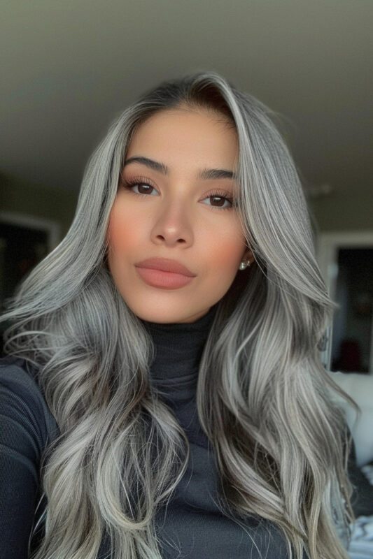 Woman with long, wavy silver hair and shadow roots