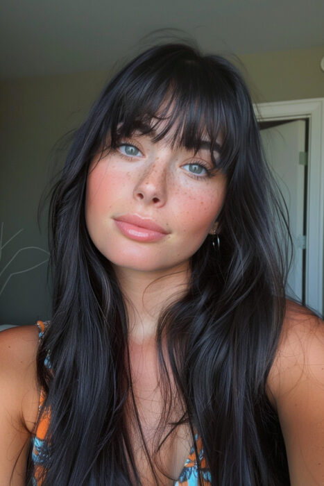 Woman with long black hair and curtain bangs.