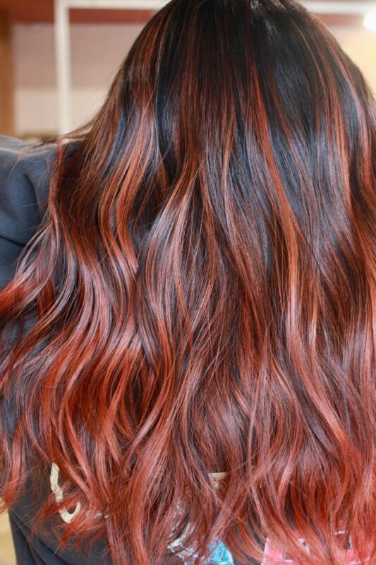 Woman with auburn balayage on her dark brown hair.