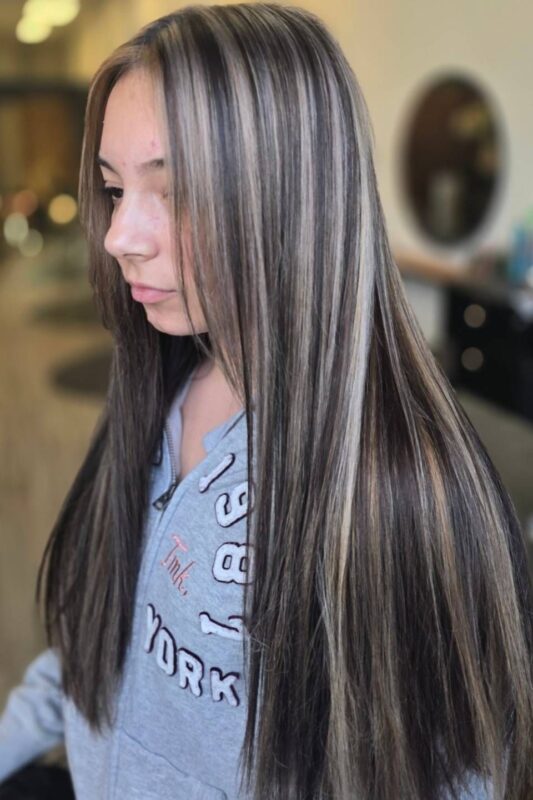 Woman with black hair and beige-blonde highlights.