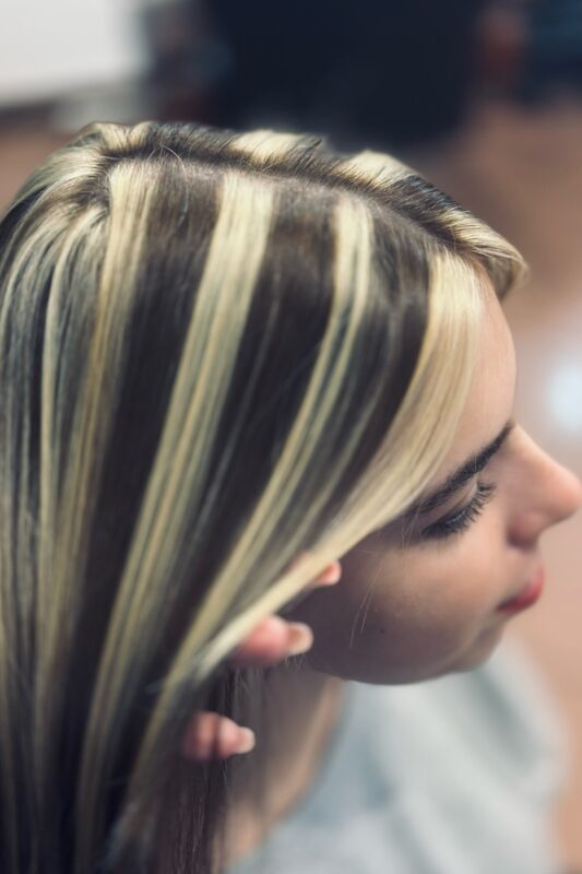 Woman with black hair and thick butter blonde highlights.