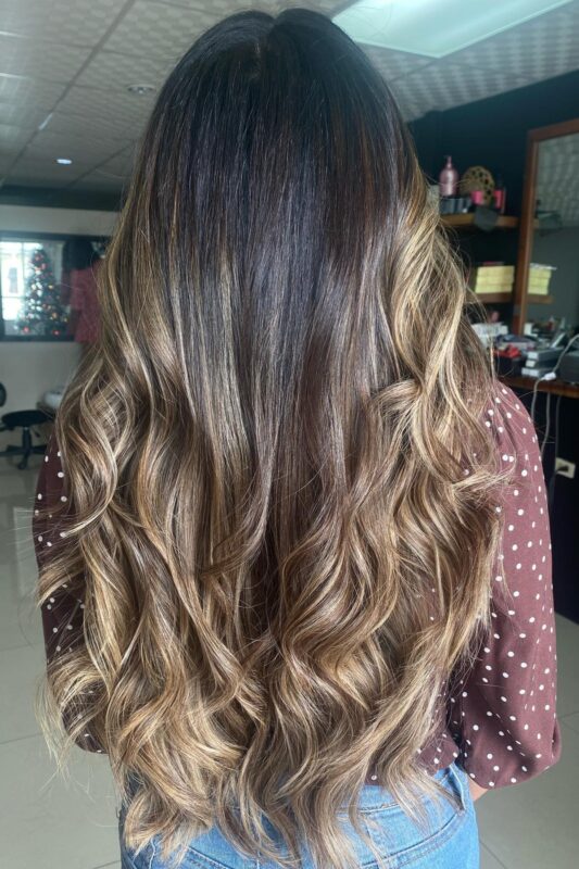 Woman with blonde balayage on dark brown hair.