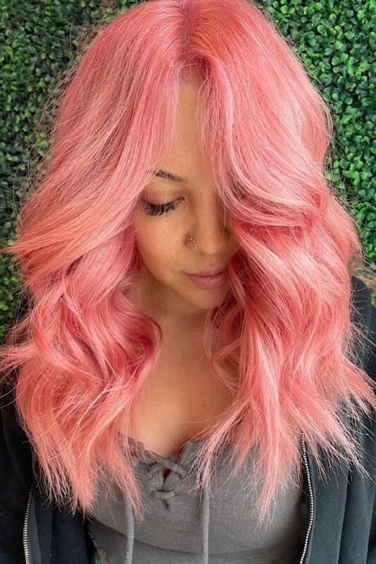 Woman with bright peach pink hair.