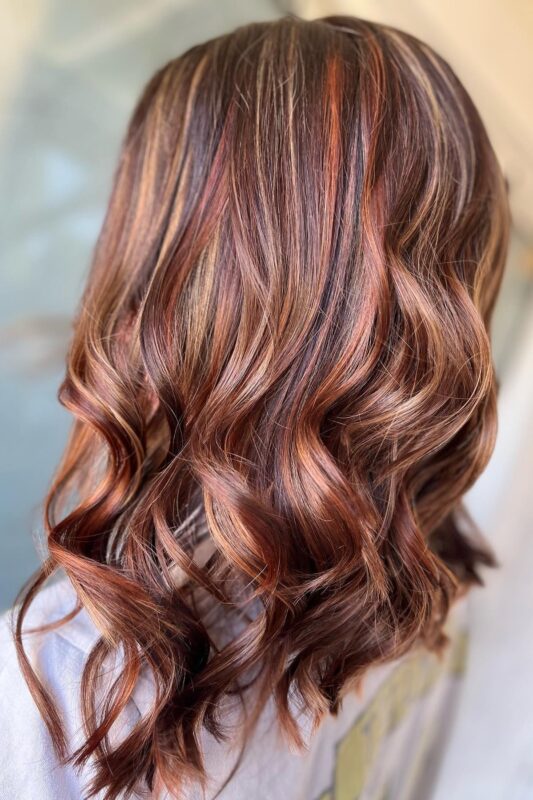 Woman with brown hair highlighted with auburn and caramel.