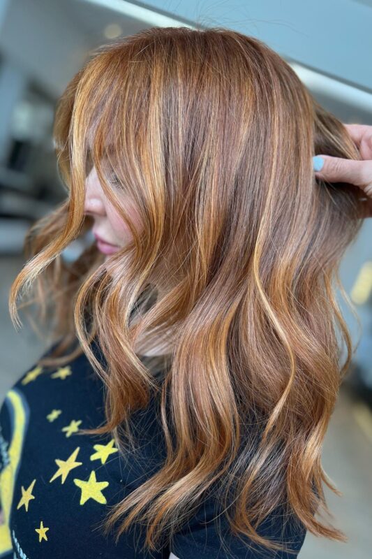 Woman with brown hair featuring vibrant copper highlights.