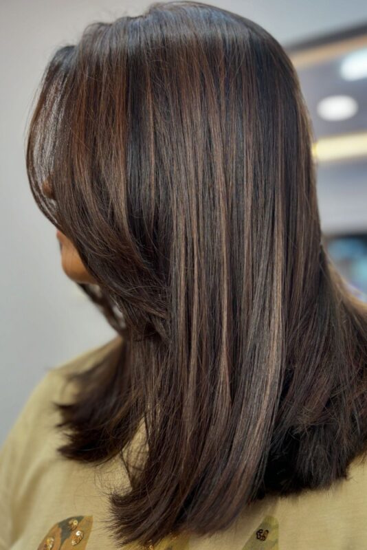 Woman with wavy brown hair and light brown highlights.