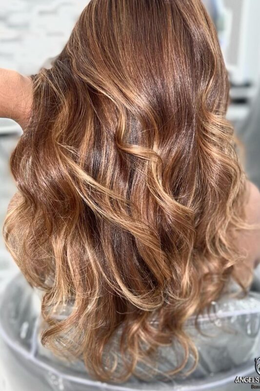 Woman with dark brown hair and caramel and blonde highlights.