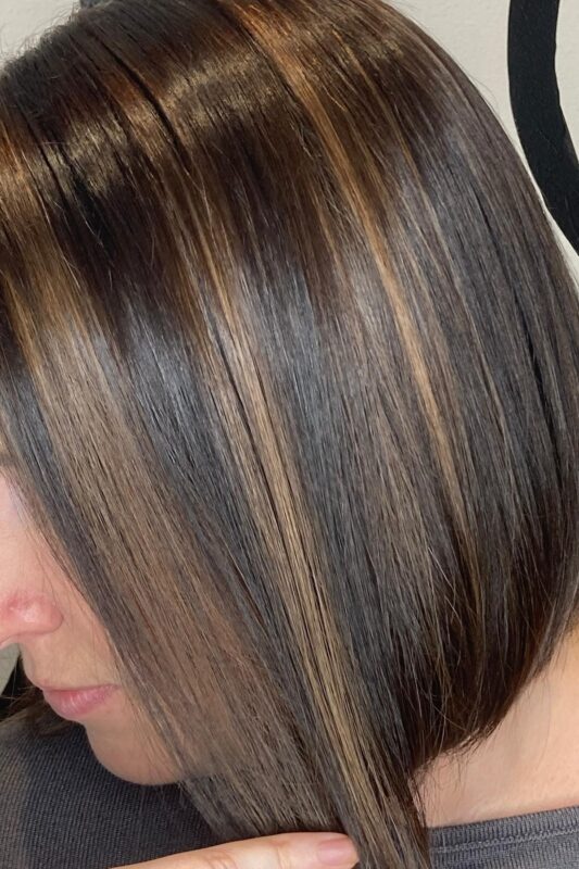 Woman with chocolate brown hair enriched with subtle caramel highlights.