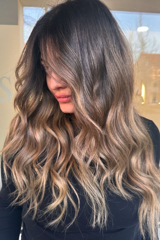 Mujer con cabello castaño chocolate y balayage bronceado.