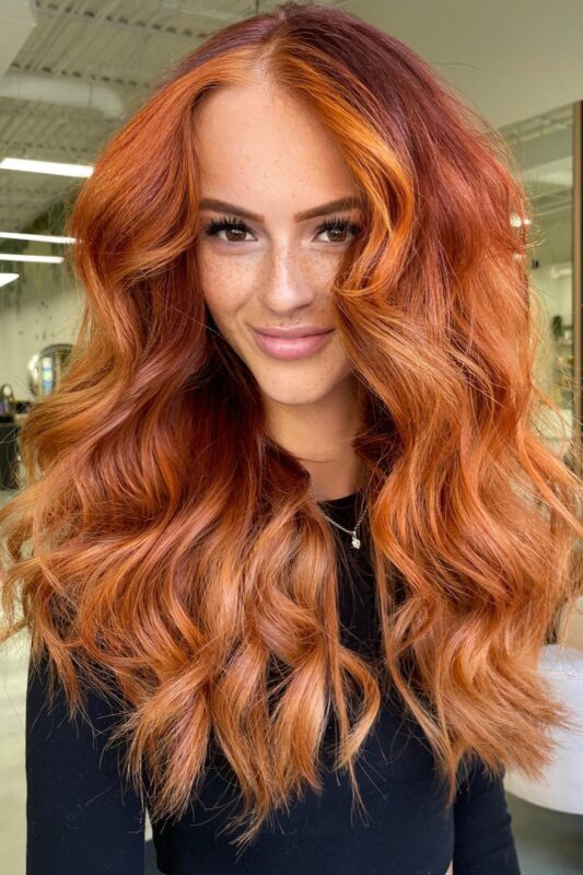 Woman with a copper balayage on her red hair.