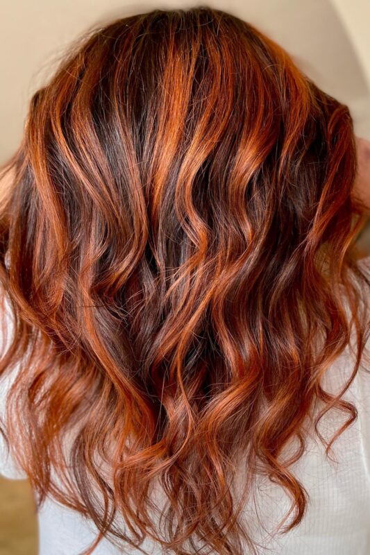 Woman with copper highlights on dark brown hair.