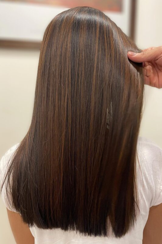 Woman with dark brown hair highlighted with light brown and golden blonde tones.