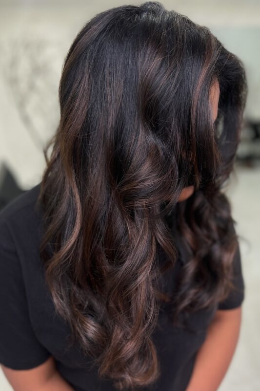 Woman with dark brown hair and mocha highlights.