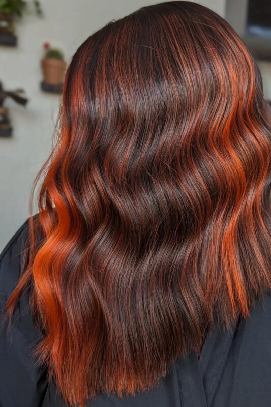 Woman with dark brown hair and orange highlights.