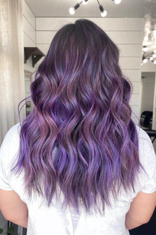 Woman with dark brown hair featuring vibrant purple highlights.