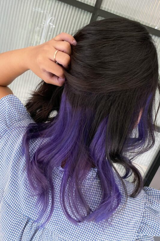 Woman with dark brown hair and purple underneath.