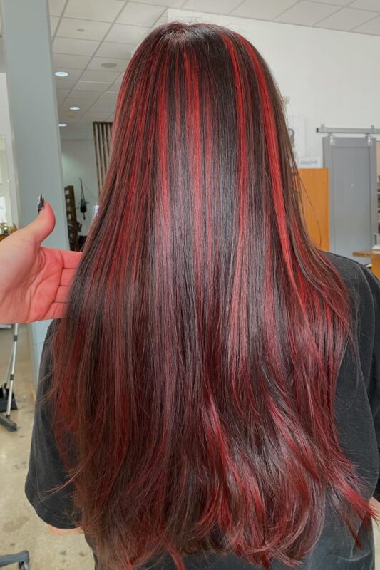 Woman with dark brown hair and red highlights.