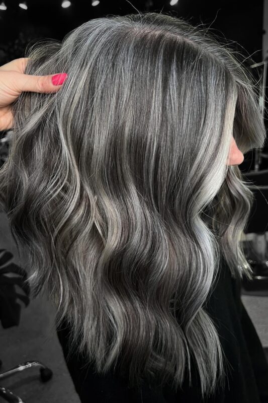 Woman with dark hair with silver highlights and a platinum money piece.