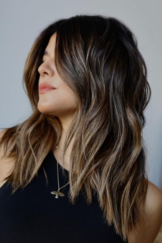 Woman with golden brown highlights on dark brown hair.