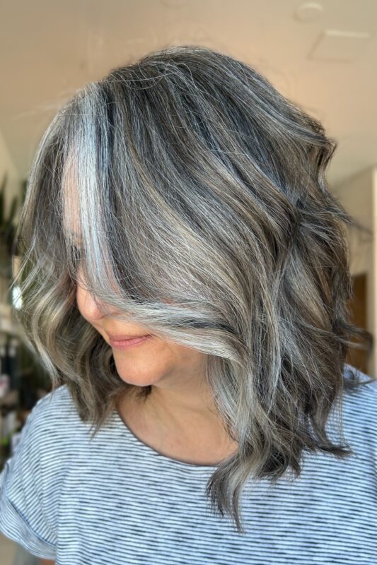 Woman with dynamic gray and white highlights in brown hair.