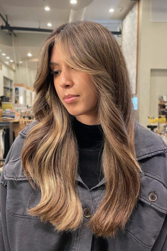 Woman with honey balayage on dark brown hair.