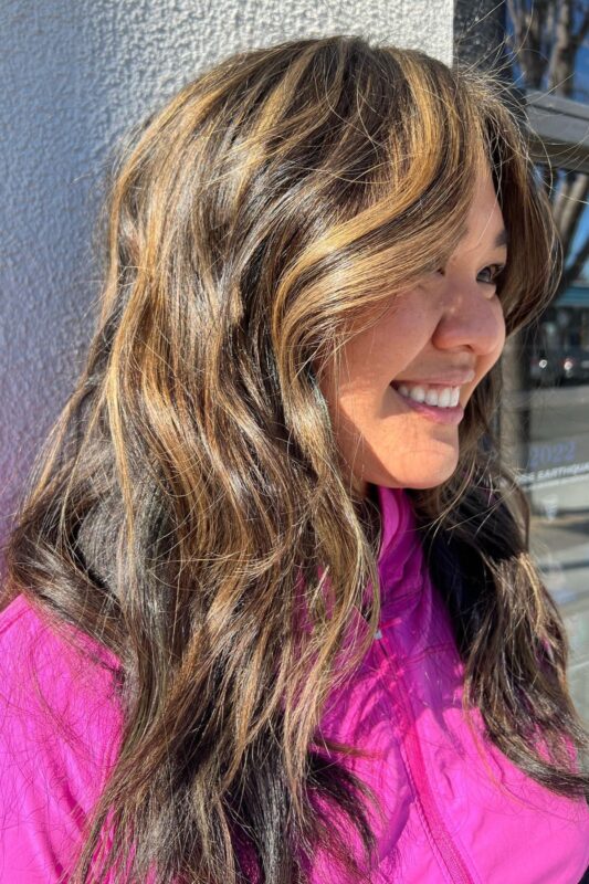 Woman with honey blonde highlights on dark brown hair.