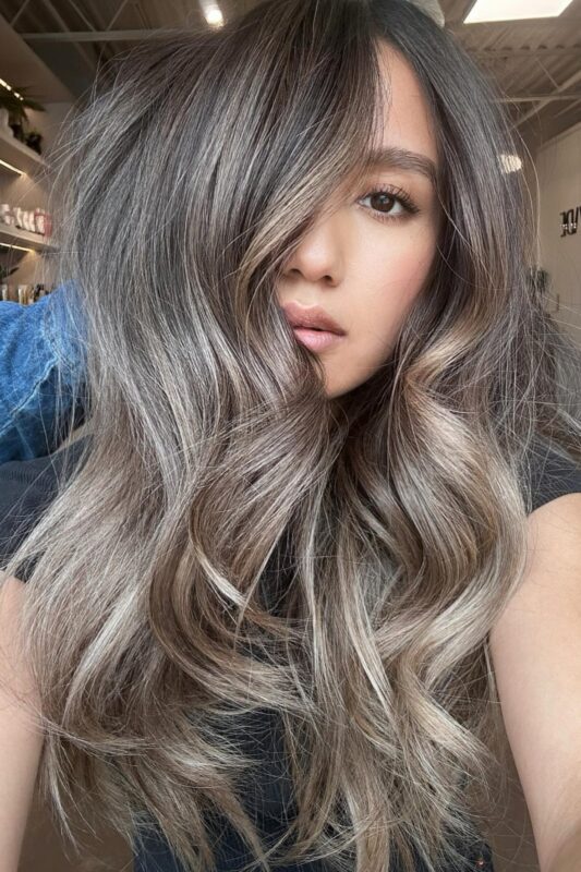 Woman with medium brown hair and ashy blonde balayage.