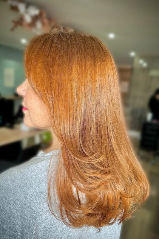 Woman with natural copper hair color cascading down her back.