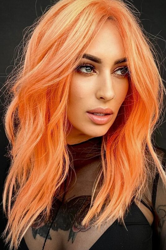 Woman with a neon peach hair color.