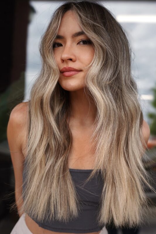 Woman with pale ash blonde balayage on medium brown hair.