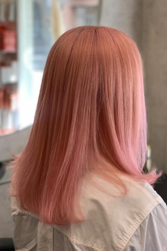 Woman with pastel pink rose gold hair.