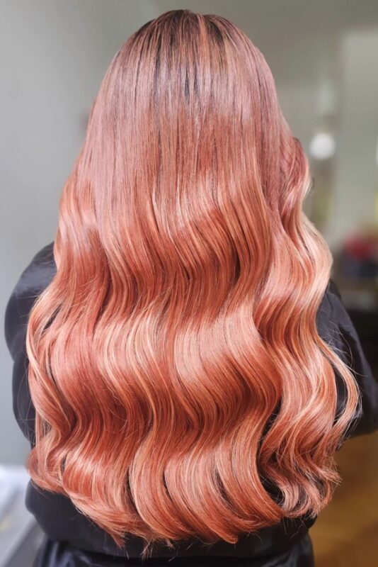 Mujer con cabello color rosa melocotón.